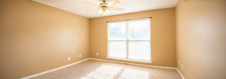 Freshly painted empty bedroom with new carpet and ceiling fan